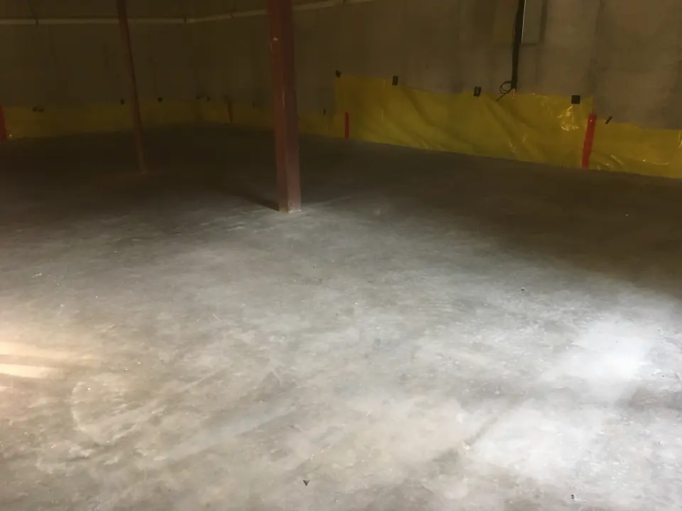 Finished basement slab with vapor barrier still seen on the walls.