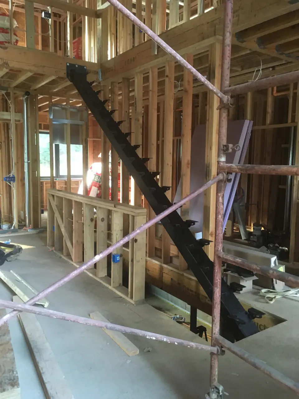 The first-floor staircase beam is installed. The staircases came in partially pre-assembled with step brackets bolted in. The three and a ha
